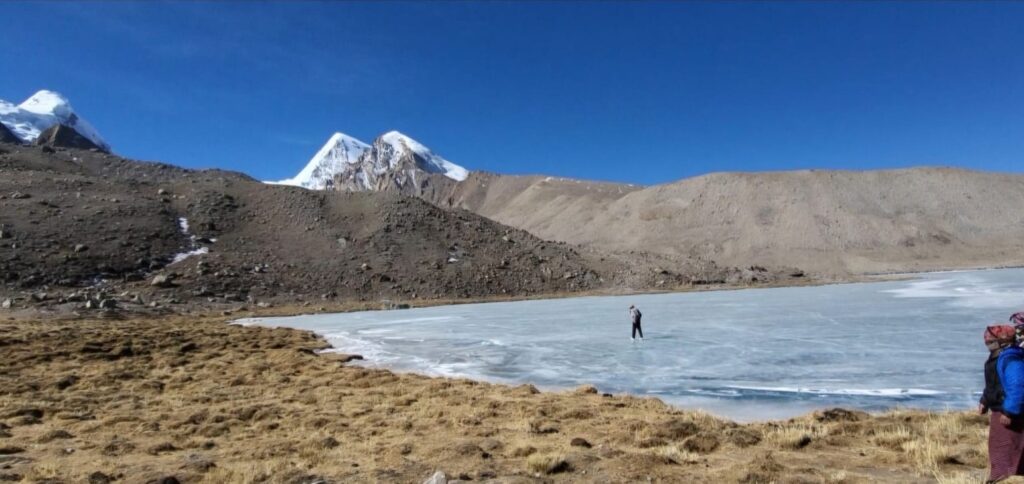 an elderly man walking on frozen gurudongmar lake in north sikkim